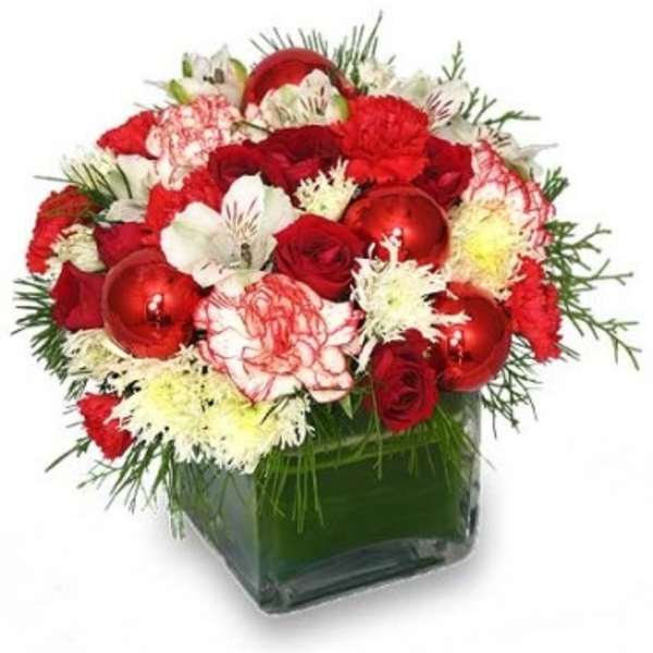 Compact red and white floral arrangement with ornaments in a clear glass cube vase