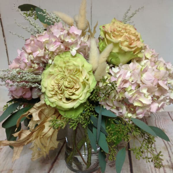 Pastel arrangement of green roses and pink hydrangeas in a clear glass vase