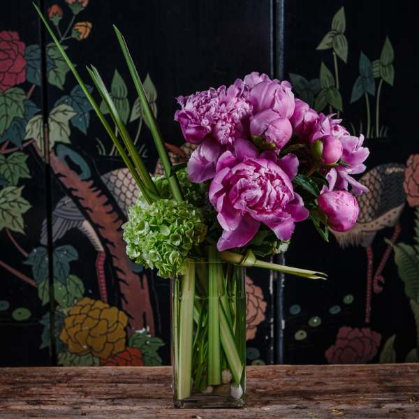 Pink peonies and green hydrangea in a clear glass vase