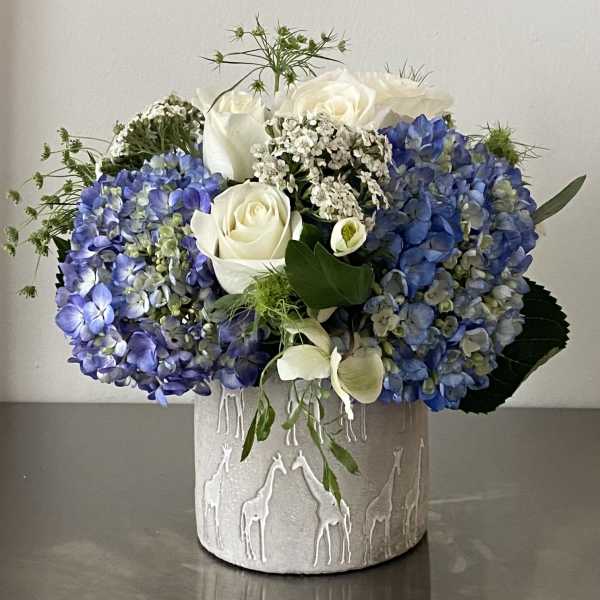 Blue hydrangeas and white roses arranged in a textured vase