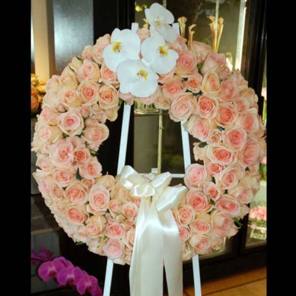 Heart-shaped wreath of pale pink roses with white orchids and a satin ribbon