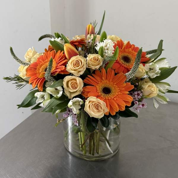 Orange gerbera daisies and cream roses in a glass vase