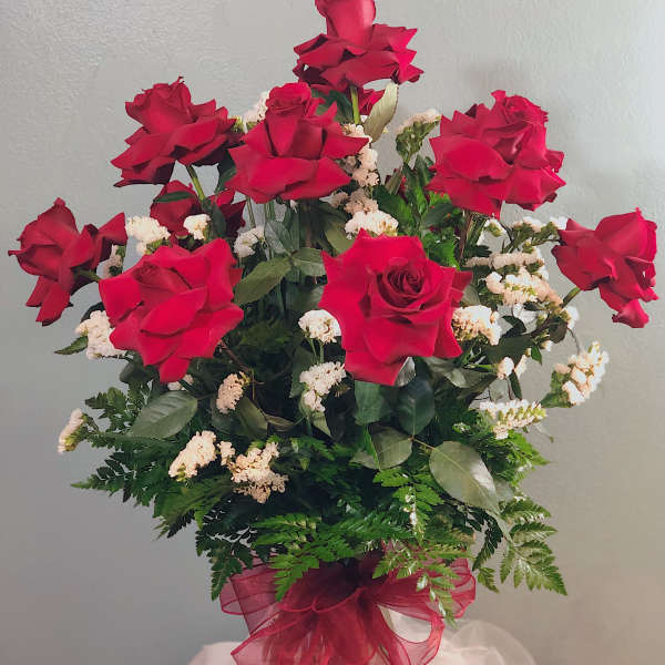 Red roses arranged in a clear glass vase with white filler flowers