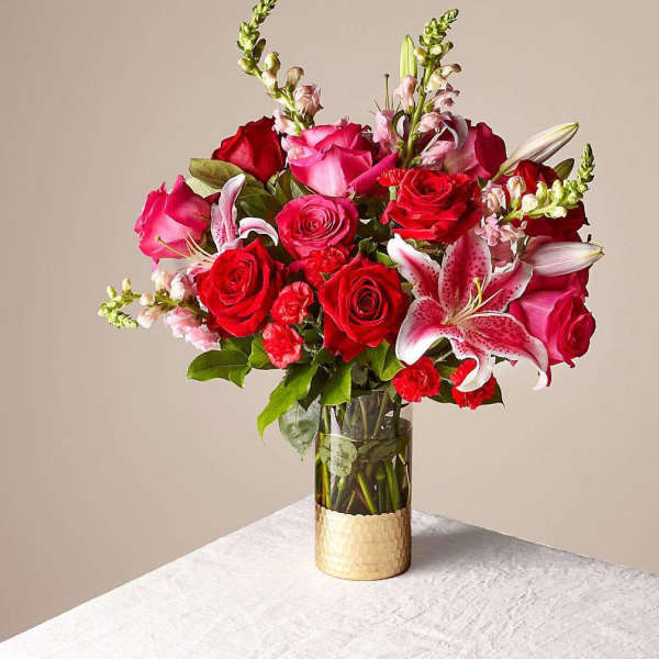 Bouquet of red and pink roses with lilies in a glass vase