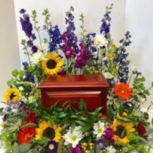 Colorful floral spray surrounding a red casket