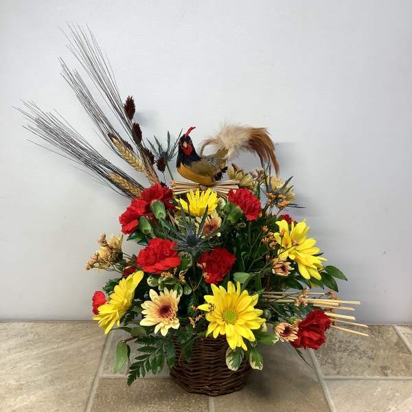 Basket arrangement with red and yellow flowers and a decorative rooster topper