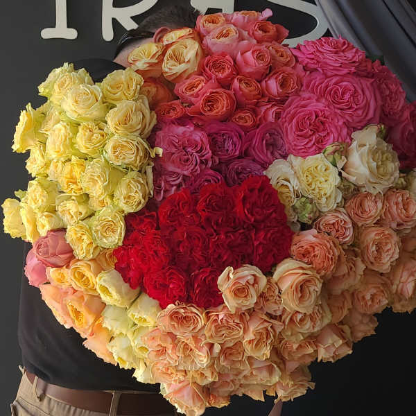 Large bouquet of multicolored roses held against a dark background