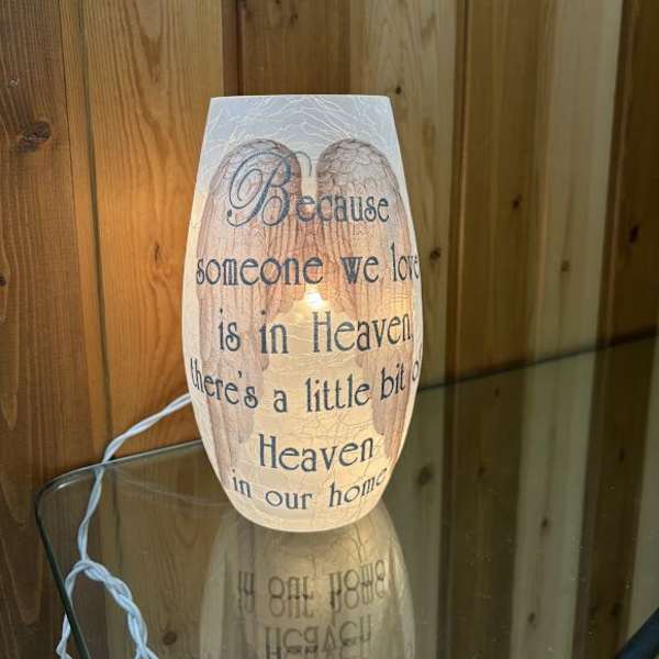 Lit memorial candle with sympathy text on a glass holder