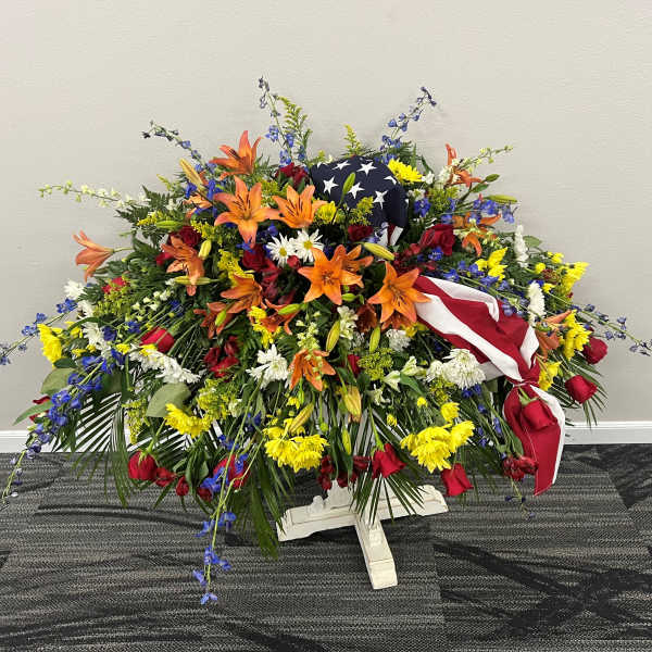 Large patriotic floral spray with red, white, and blue flowers and an American flag