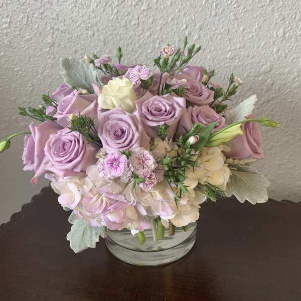 Lavender roses and pale hydrangeas in a clear glass vase