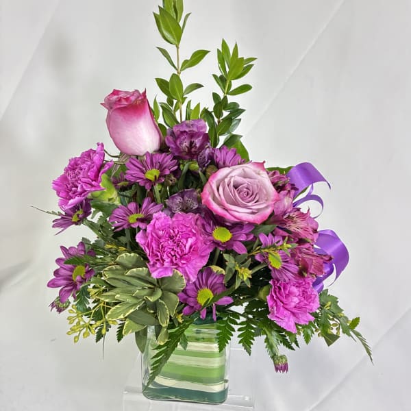 Pink and purple bouquet in a clear square vase
