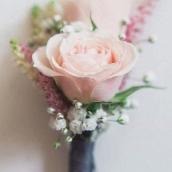 Blush rose boutonniere with small white and pink accent flowers