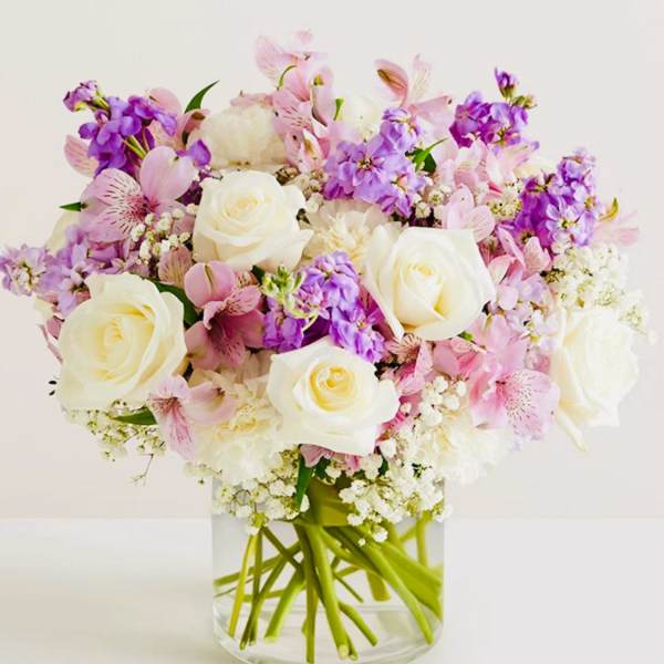 Pink and purple bouquet with white roses in a clear glass vase