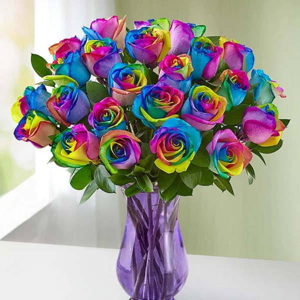 Bouquet of rainbow-colored roses in a purple glass vase