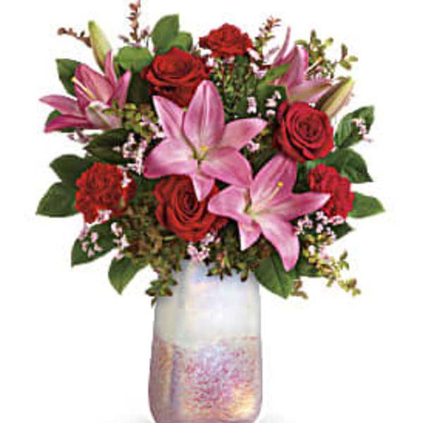 Pink lilies and red roses arranged in a frosted glass vase