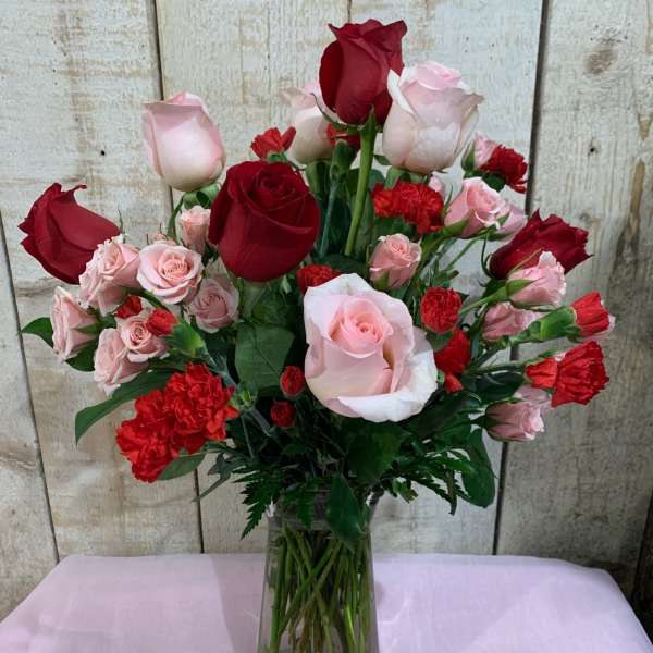 Bouquet of red and pink roses with carnations in a glass vase