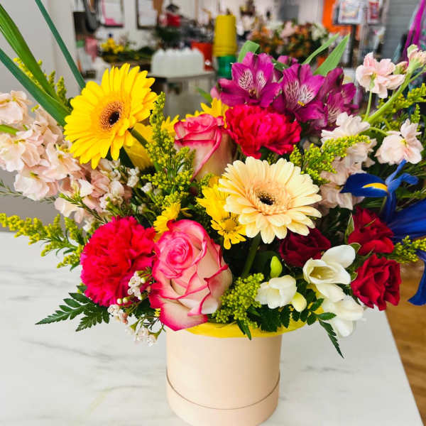Colorful mixed bouquet in a round box with roses and gerberas