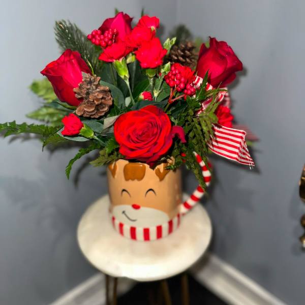 Red roses and carnations in a festive Santa mug with ribbon