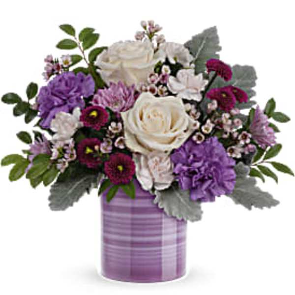 Lavender and white mixed flower arrangement with roses and carnations in a purple striped ceramic vase
