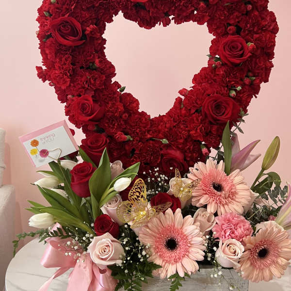Heart-shaped red flower arrangement with pink blooms in a wooden box