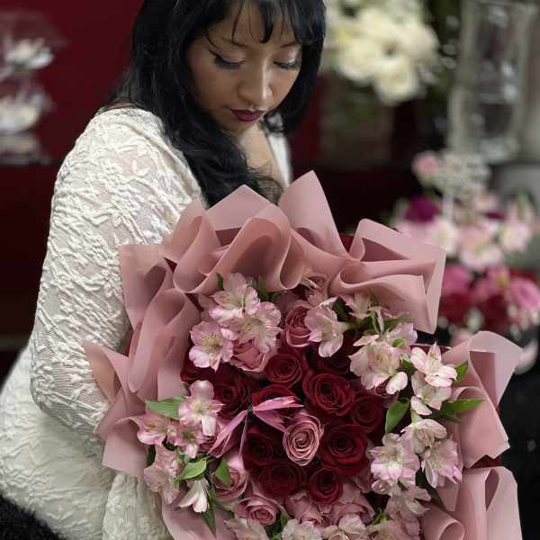 Woman holding a bouquet of pink and red roses with pale pink flowers