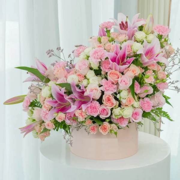 Large pink and white floral arrangement in a round box