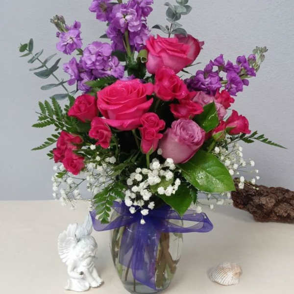 Pink and purple rose bouquet in a glass vase with a purple ribbon
