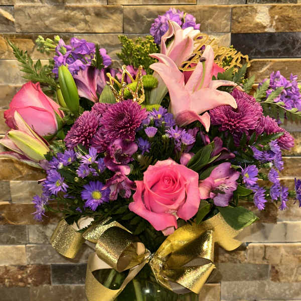 Pink roses and lilies in a glass vase with a gold ribbon