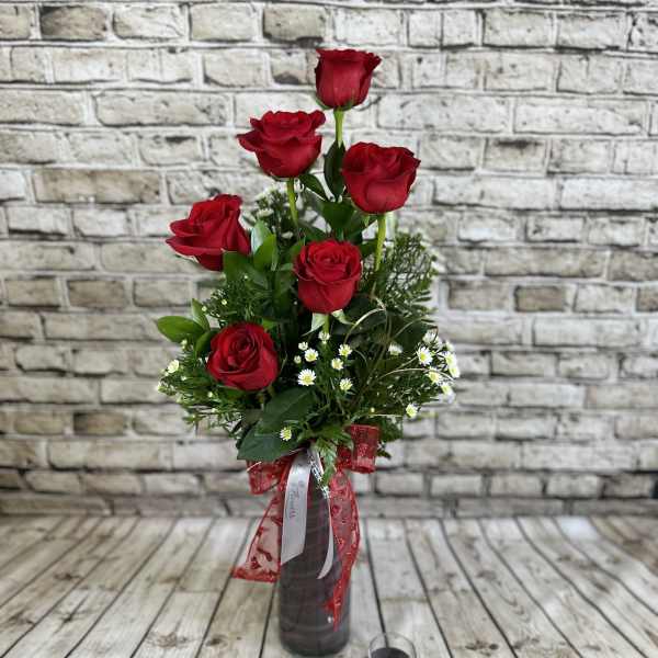 Tall bouquet of red roses in a dark vase with a red ribbon