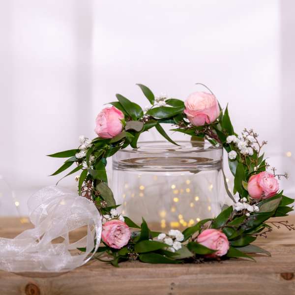 Pink flower crown with ribbon on a glass vase