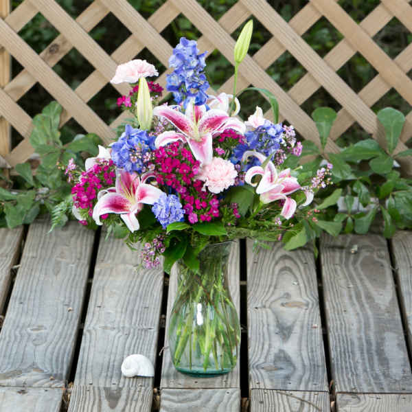 Pink lilies and blue flowers in a glass vase