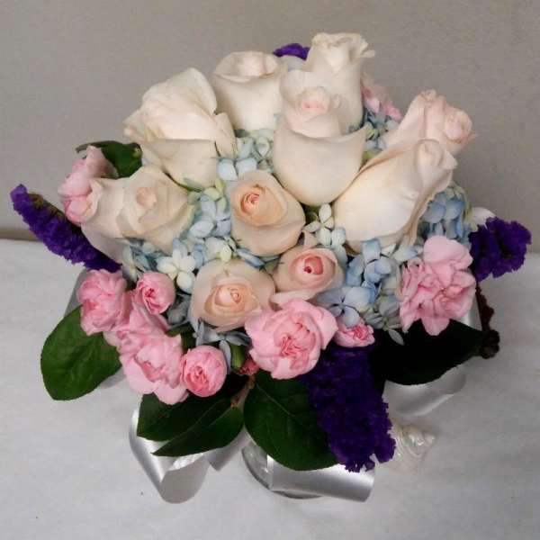 Bouquet of white roses, pink carnations, and blue hydrangeas with purple accents