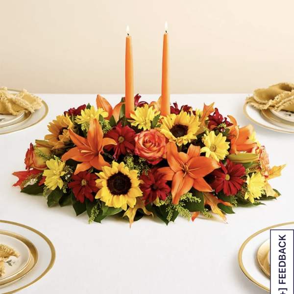 Low floral centerpiece with orange candles and mixed autumn blooms
