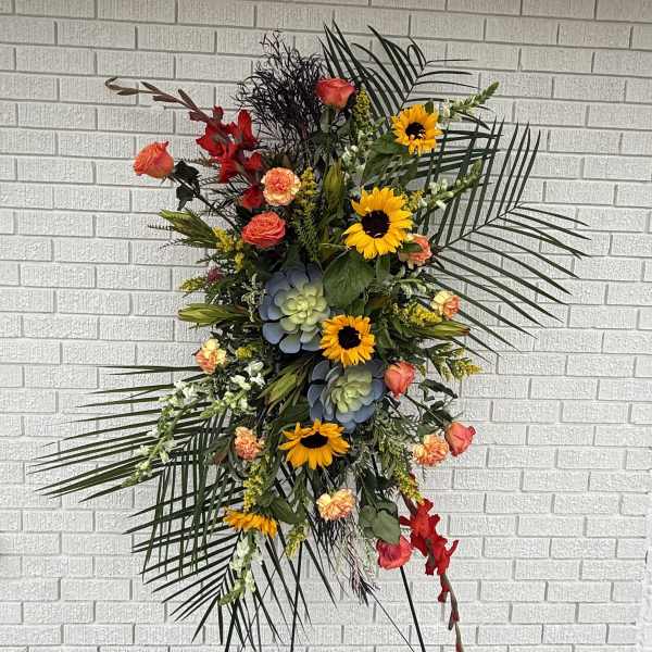 Tall floral standing spray with sunflowers, roses, and succulents