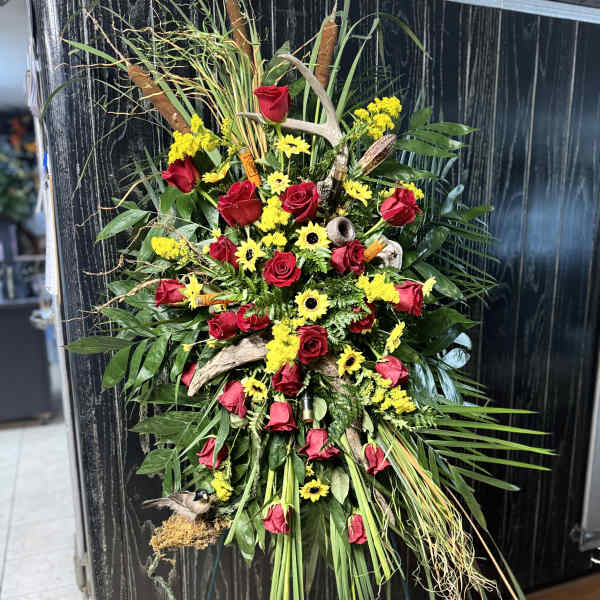 Standing floral spray with red roses and yellow daisies on a wire easel