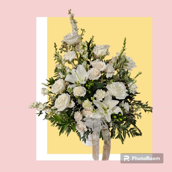 White rose and lily arrangement in a white vase with ribbon