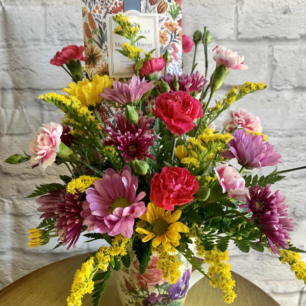 Mixed bouquet of pink, yellow, and purple flowers in a floral vase