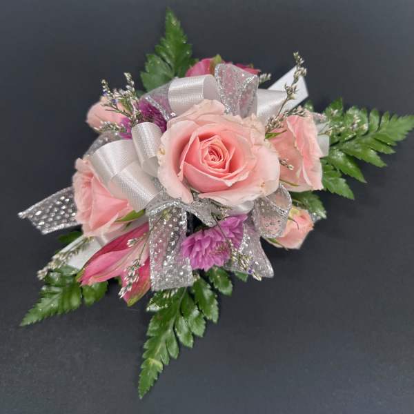 Pink rose corsage with silver ribbon and green fern accents