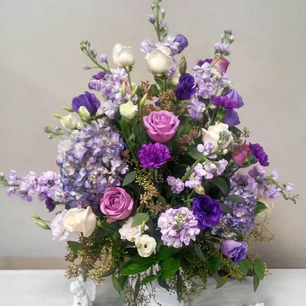 Purple and white floral arrangement in a white vase