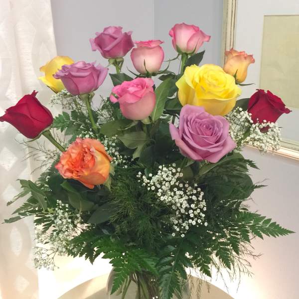 Mixed roses in a clear glass vase with baby's breath