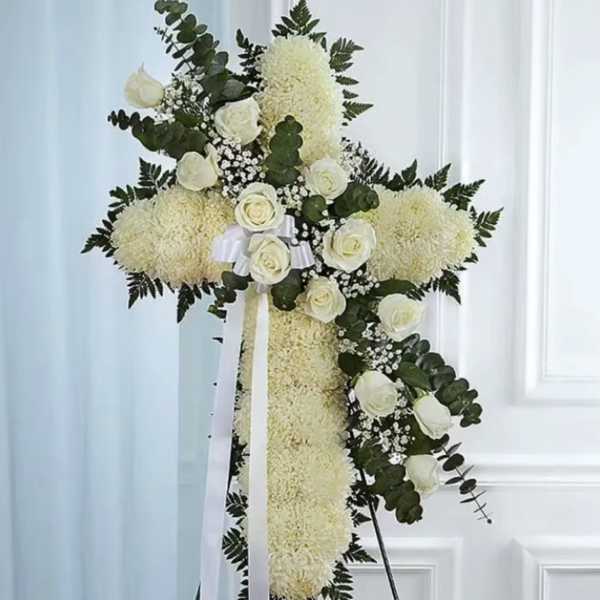 White floral cross on an easel with ribbon