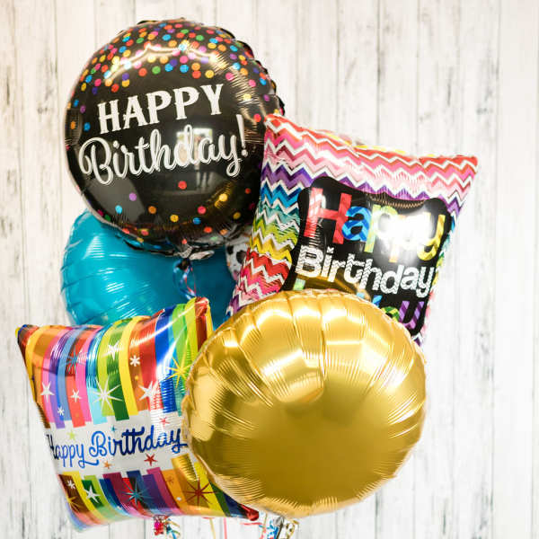 Cluster of birthday balloons with a candle and small gift on a table