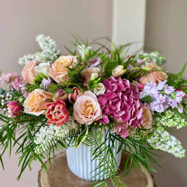 Pink and peach roses with hydrangeas in a white vase