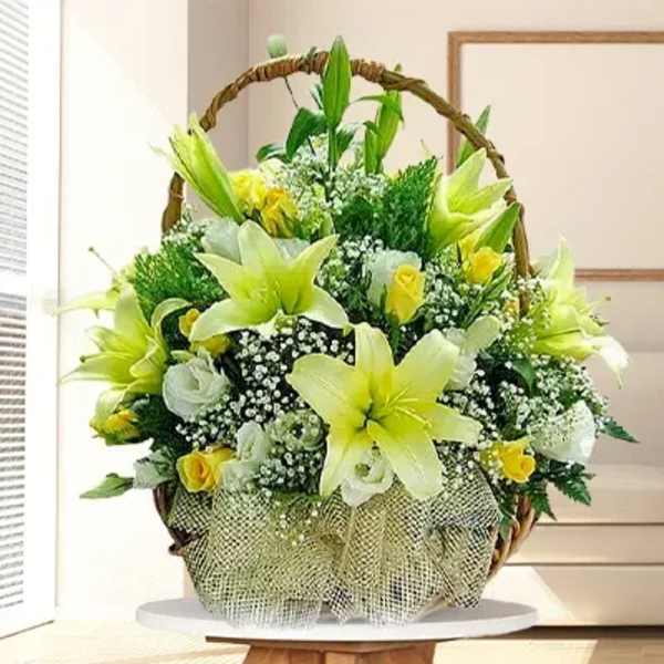 Basket arrangement of yellow lilies and white roses with baby's breath