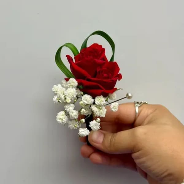 Red rose boutonniere with white baby's breath and green loops