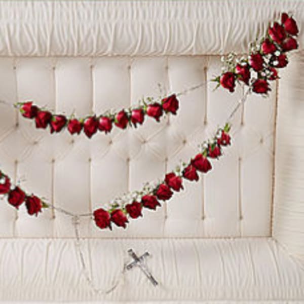 Red rose garlands draped across a white tufted headboard