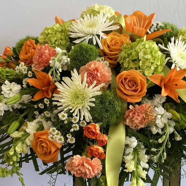 Orange, white, and green floral spray with ribbon accents