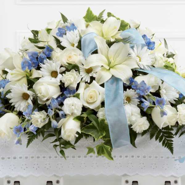 White floral arrangement with blue ribbon and blue accents
