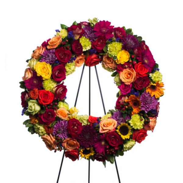 Circular floral wreath on a black easel with multicolored blooms