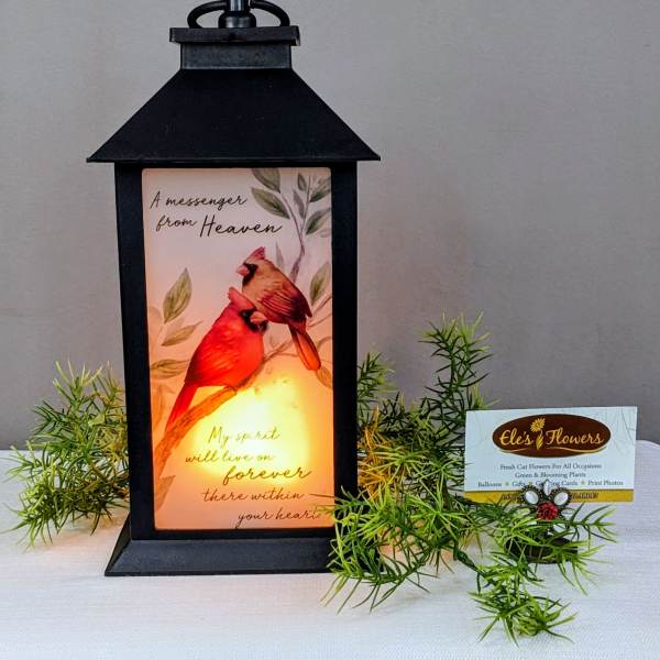 Black lantern with a memorial card and faux greenery sprigs